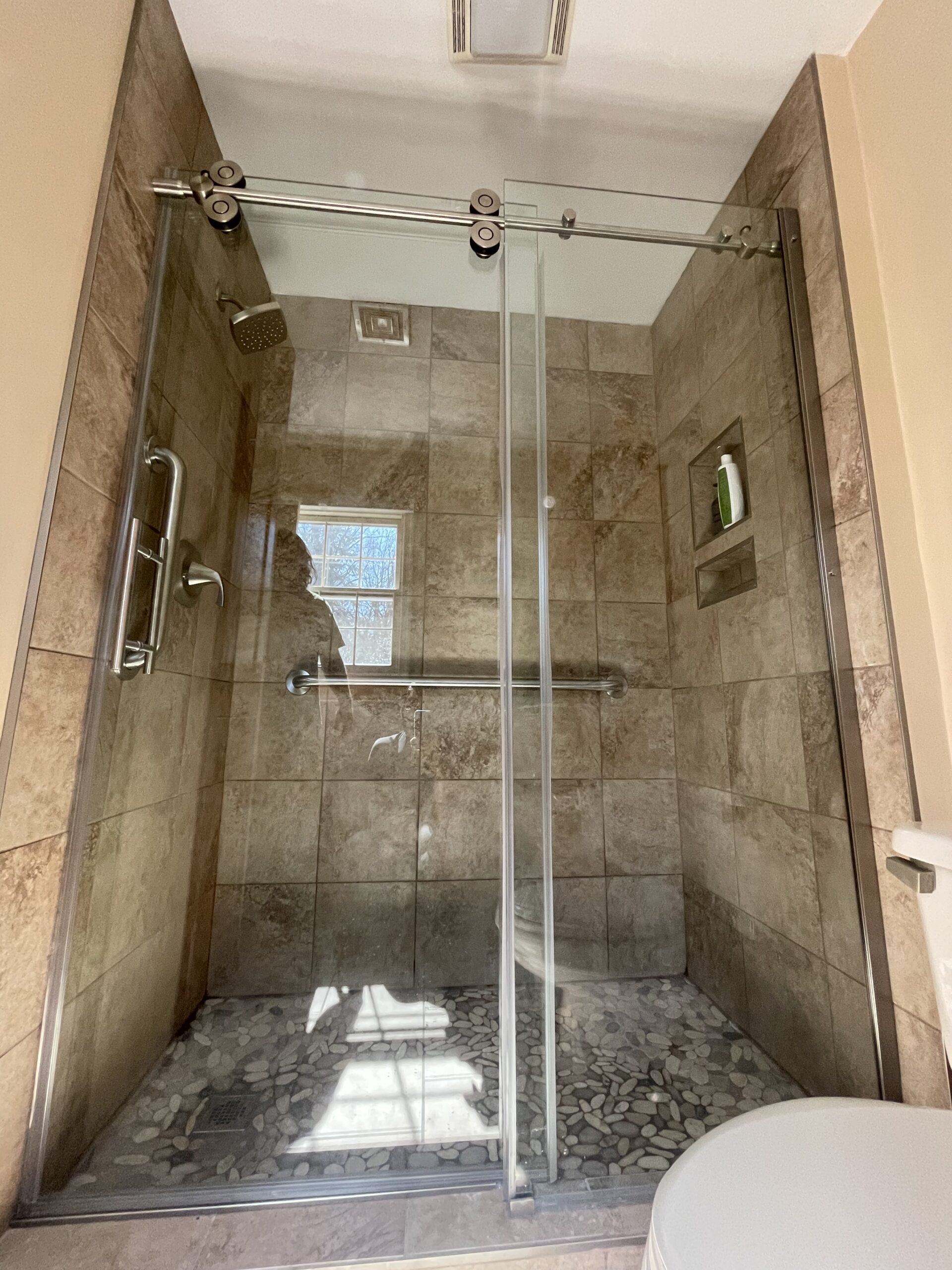 updated warm color tile shower with door
